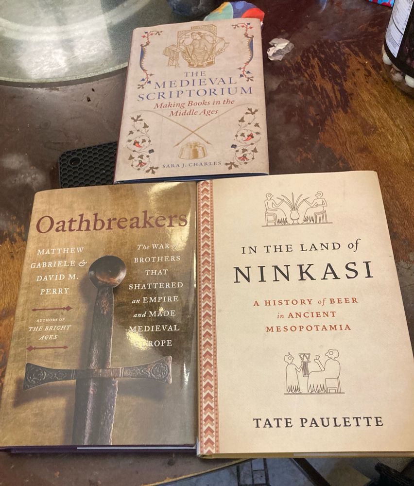 Three books on a table: The Medieval Scriptorium, Oathbreakers, and In the Land of Ninkasi
