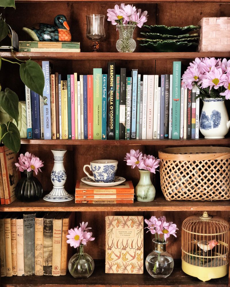 Picture of a wooden cabinet filled with books, flowers ans knick-knacks