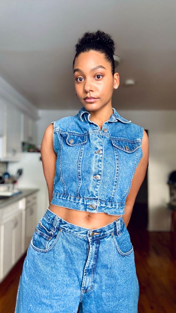Girl standing with arms crossed behind her back in a jeans outfit