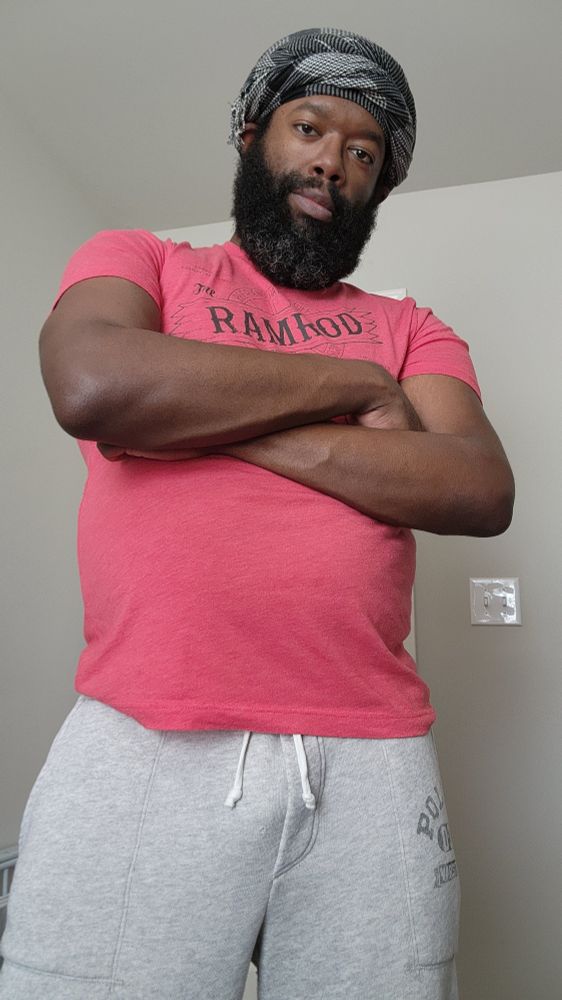 Self-portrait while standing with my arms folded and making eye contact with a subtle grin/smile.