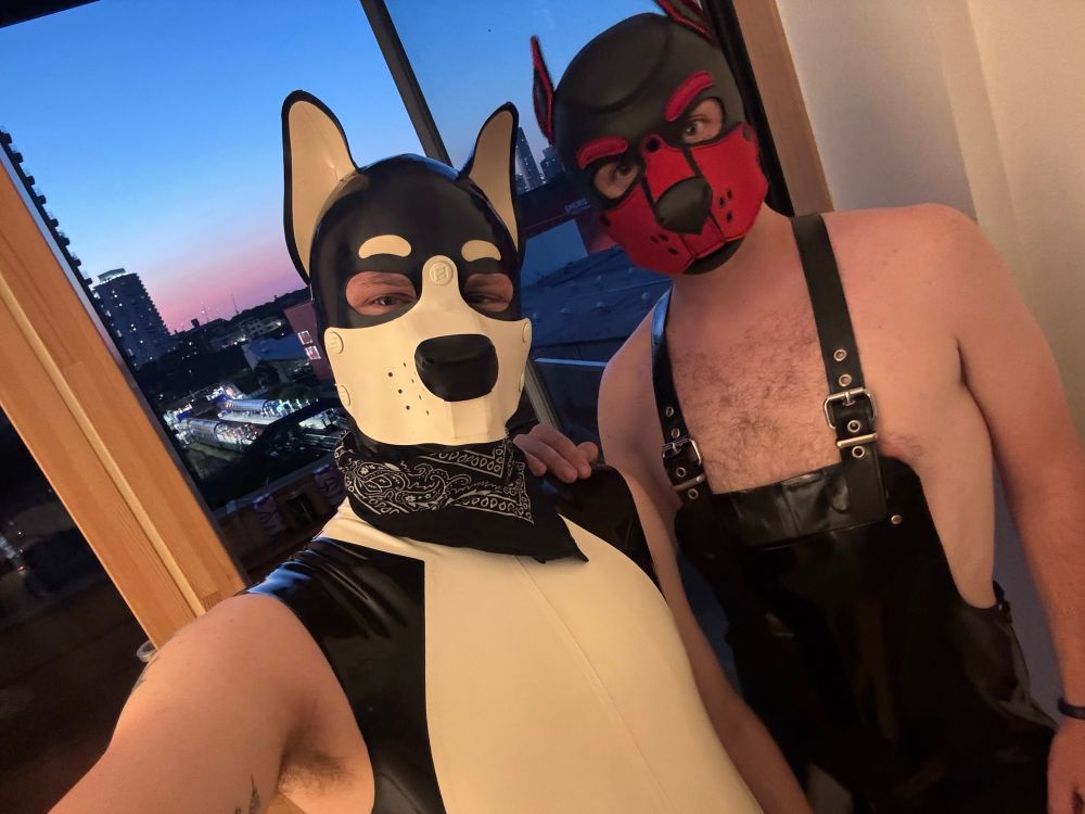 Black and white rubber dog with his red pup owner posing in front of an open window 