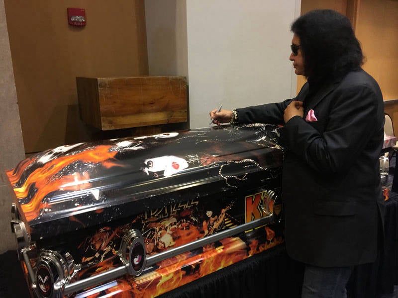Gene Simmons signing the "Kiss Kasket" a coffin emblazoned with KISS branding.
