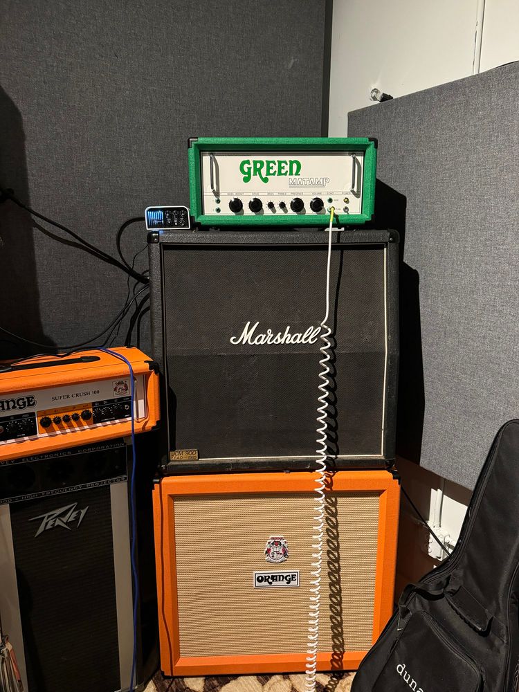 Guitar amplifier. Green matamp GT120 head, Marshall and orange cabs beneath it. 
