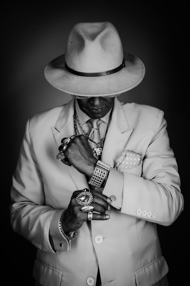 Black and white studio portraits of the same man, highlighting the textures of his suit, jewellery, and facial features. The lack of colour draws attention to contrast, expression, and detail, showing a more contemplative side of his personality.