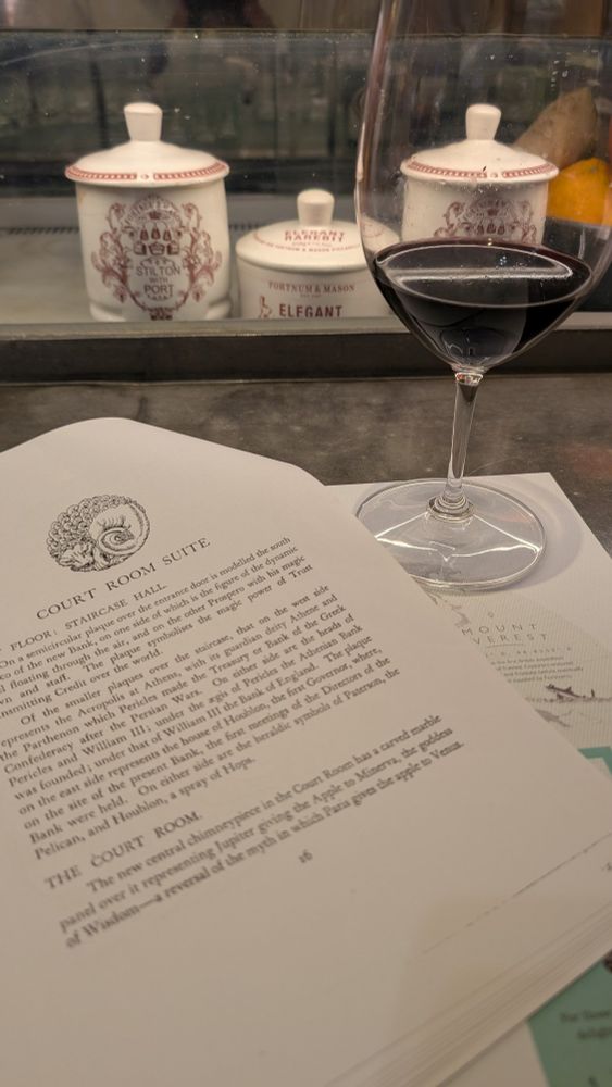 Photo of a photocopy paper with text and a glass of red wine. 