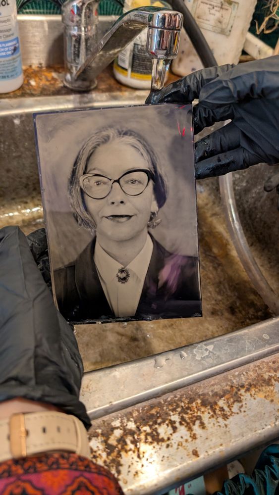 Plate of vintage image of woman with short hair wearing glasses under running water. 
