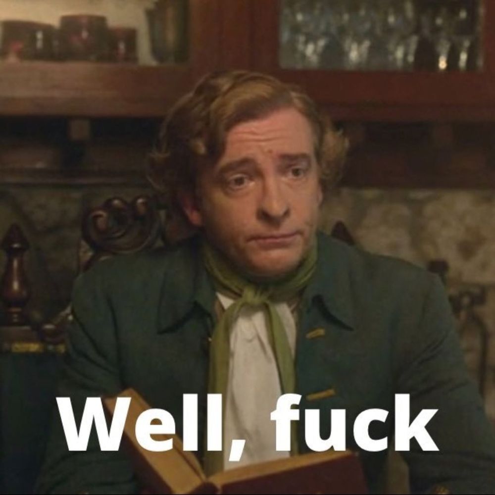 Stede Bonnet sitting at the dining table in his home. He holds an open book in his hands but is staring up into the middle distance with a look of resigned defeat. Text superimposed on the picture reads "Well, fuck".