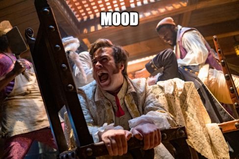 A shot from OFMD Season 1 in which the crew of the Revenge is attacking Badminton and the British soldiers in the dining room. Lucius clutches the seat of a wooden chair and screams into the void as all hell breaks loose behind him. Meme caption text at the top of the shot reads "MOOD."