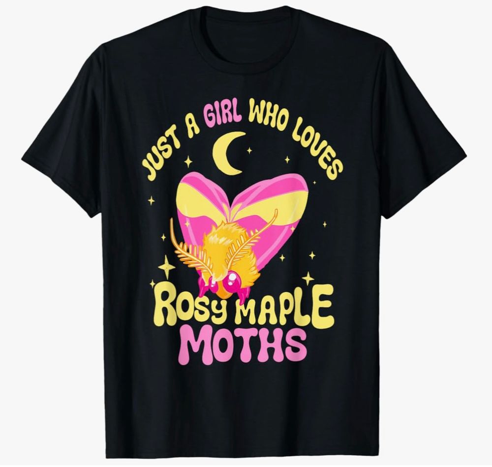 An online retail photo of a black tshirt. The design on front is a cartoony drawing of a bright pink and yellow moth with the text “Just a Girl Who Loves Rosy Maple Moths.”