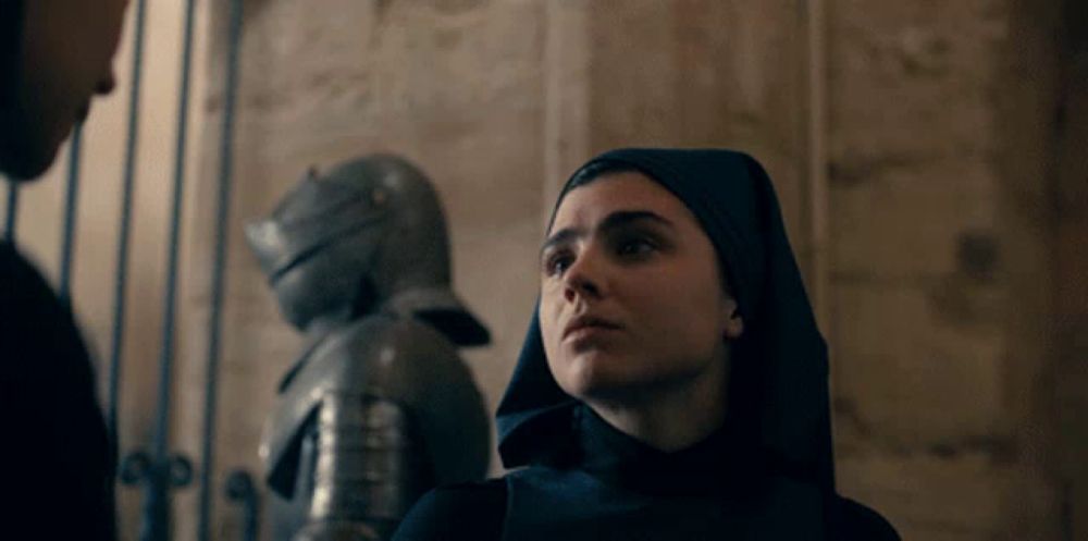 a woman in a nun 's habit looks at a man in armor