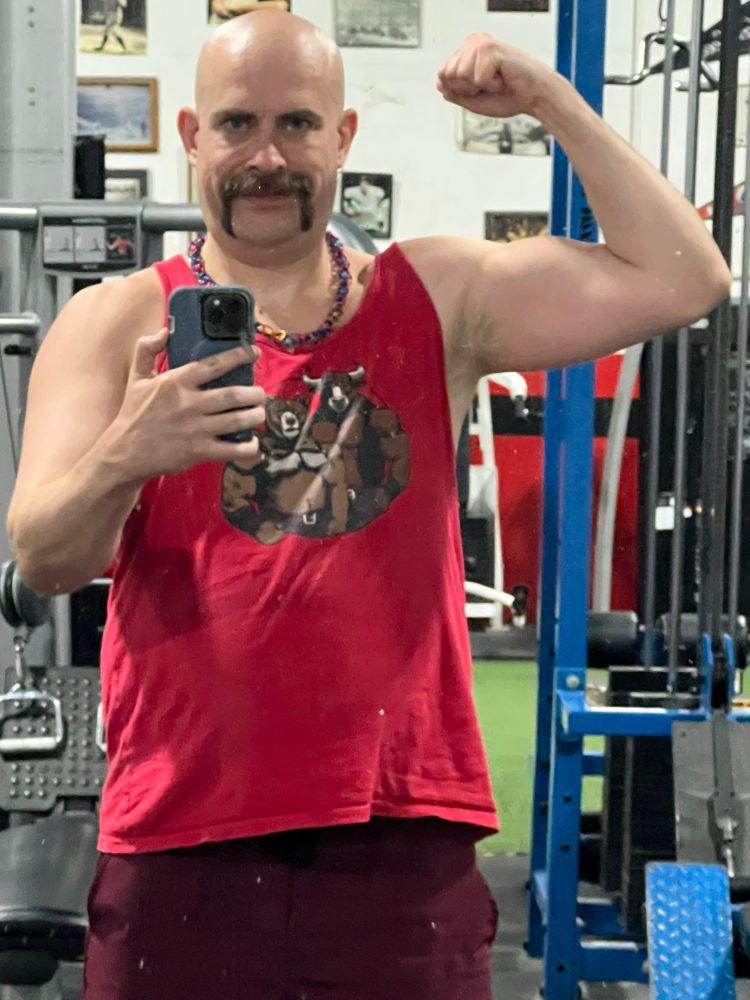 A bald mustached white man flexing