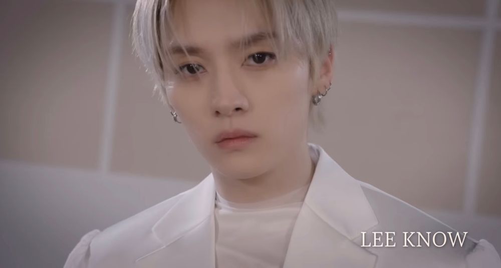 Head shot of Lee Know wearing a white tux with platinum blond hair