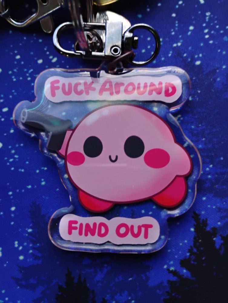 Keychain of Kirby with a gun saying "fuck around and find out"