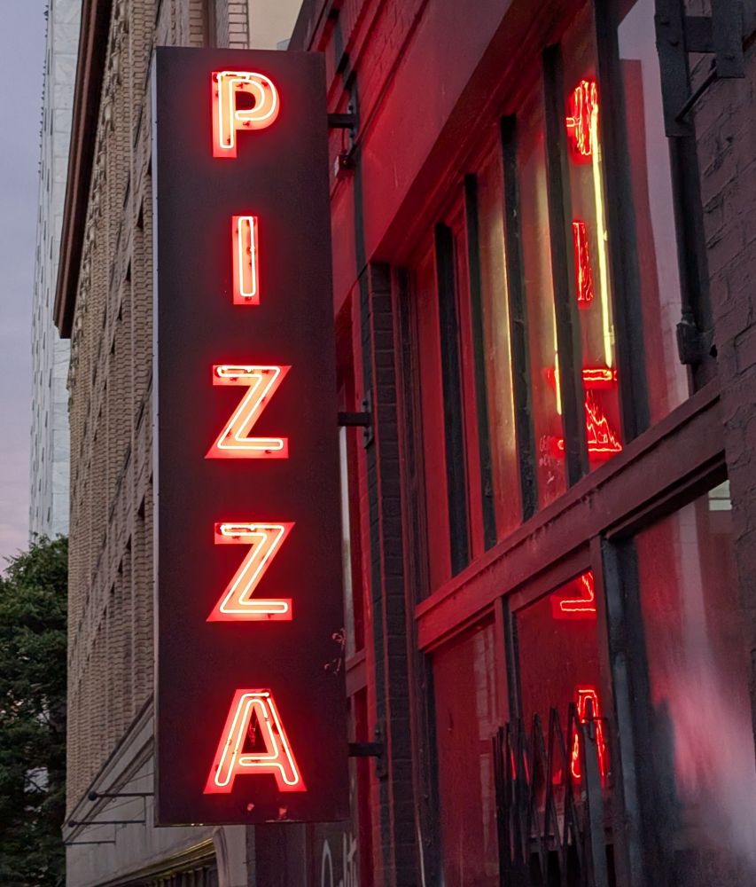 Photo of a neon sign that reads "PIZZA" vertically in Portland, OR. 