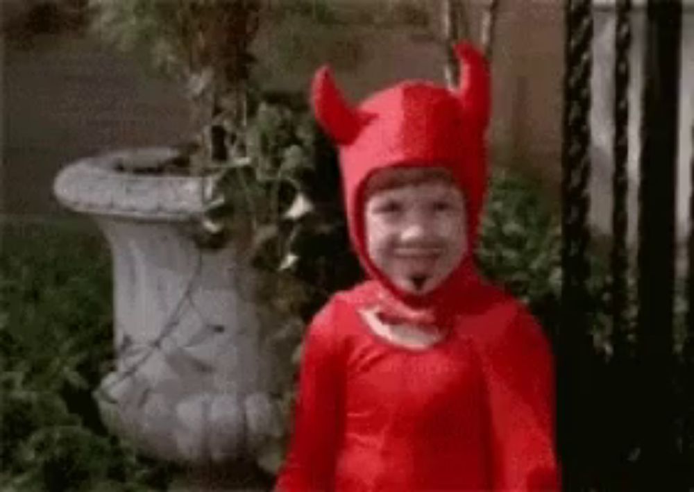 a little boy in a devil costume is smiling