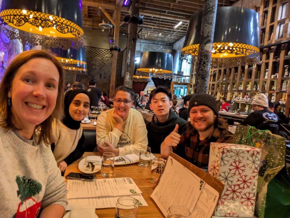 A group of five people around a table smiling in a Mexican restaurant, one with thumbs up