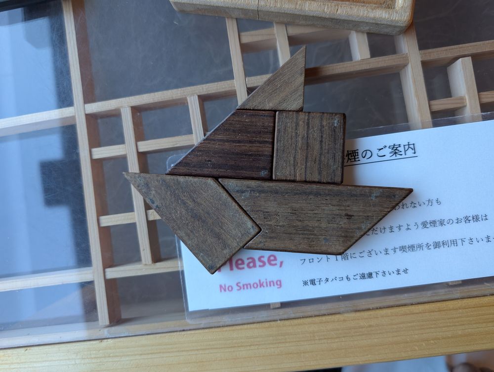 Wooden puzzle pieces arranged in an angular shape possibly resembling a sailboat.
