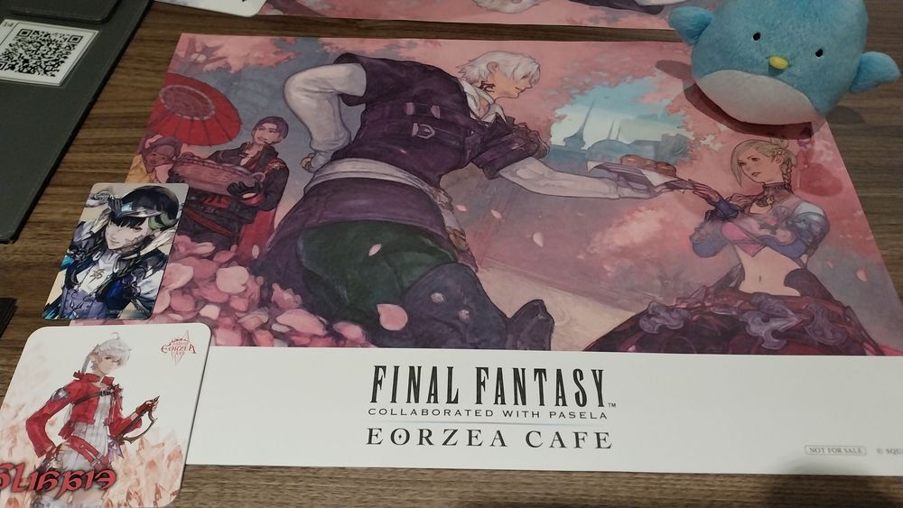 Shunta sitting on top of a ffxiv illustration, with some themed coasters in the left bottom