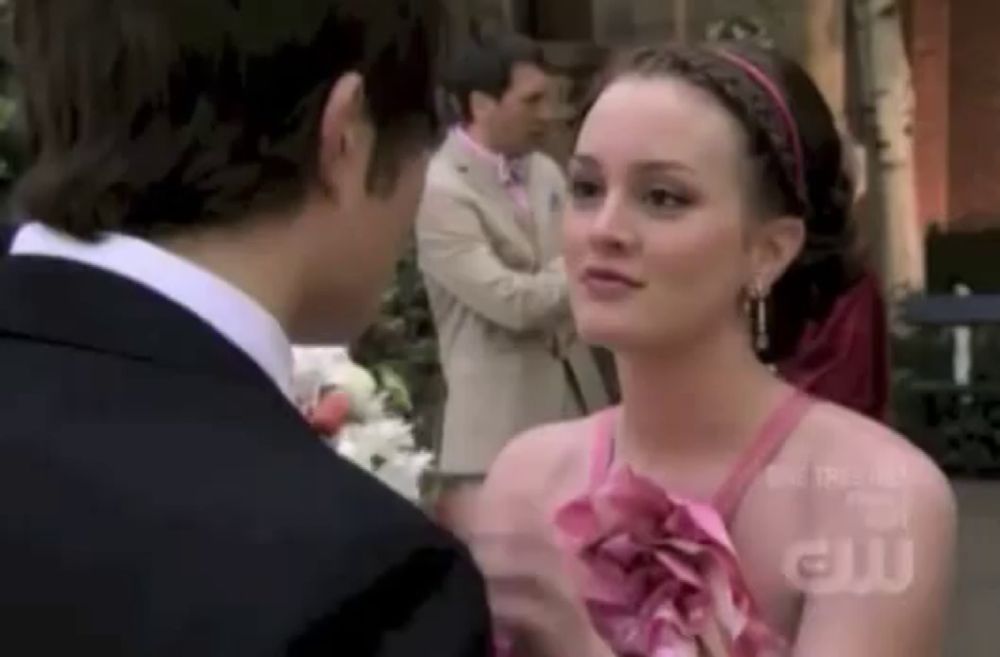 a man in a suit and a woman in a pink dress are standing next to each other and talking .