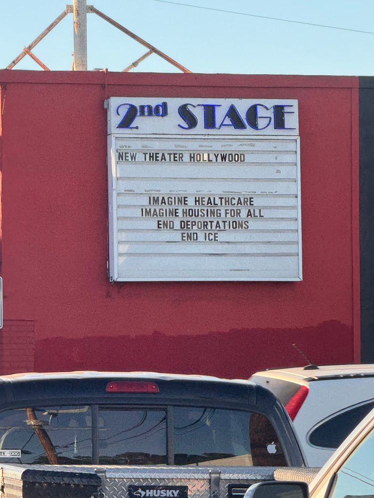 A big sign on a red theater says "2nd STAGE
NEW THEATER HOLLYWOOD
IMAGINE HEALTHCARE IMAGINE HOUSING FOR ALL END DEPORTATIONS
END ICE"