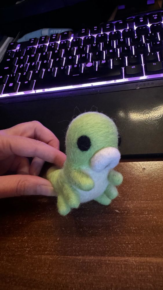 a hand holding a grub from hollow knight made out of felting wool
the stab marks on my fingers are not visible