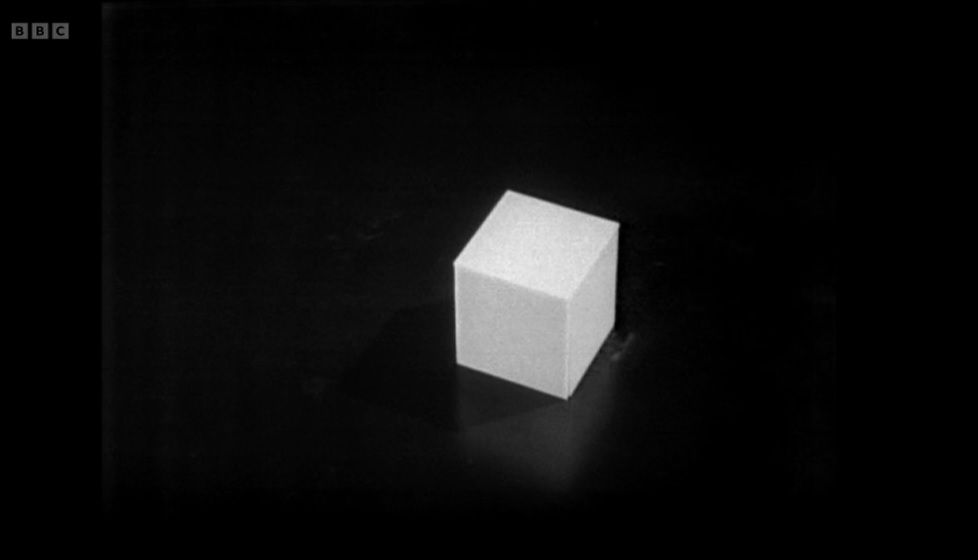 A screenshot from the eighth episode of the Doctor Who serial The War Games. A close up of a pure white cube sat on a shiny black floor.