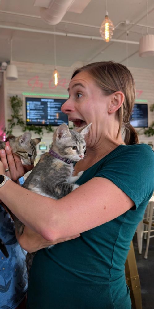 Blonde woman very excited at holding onto two kittens
