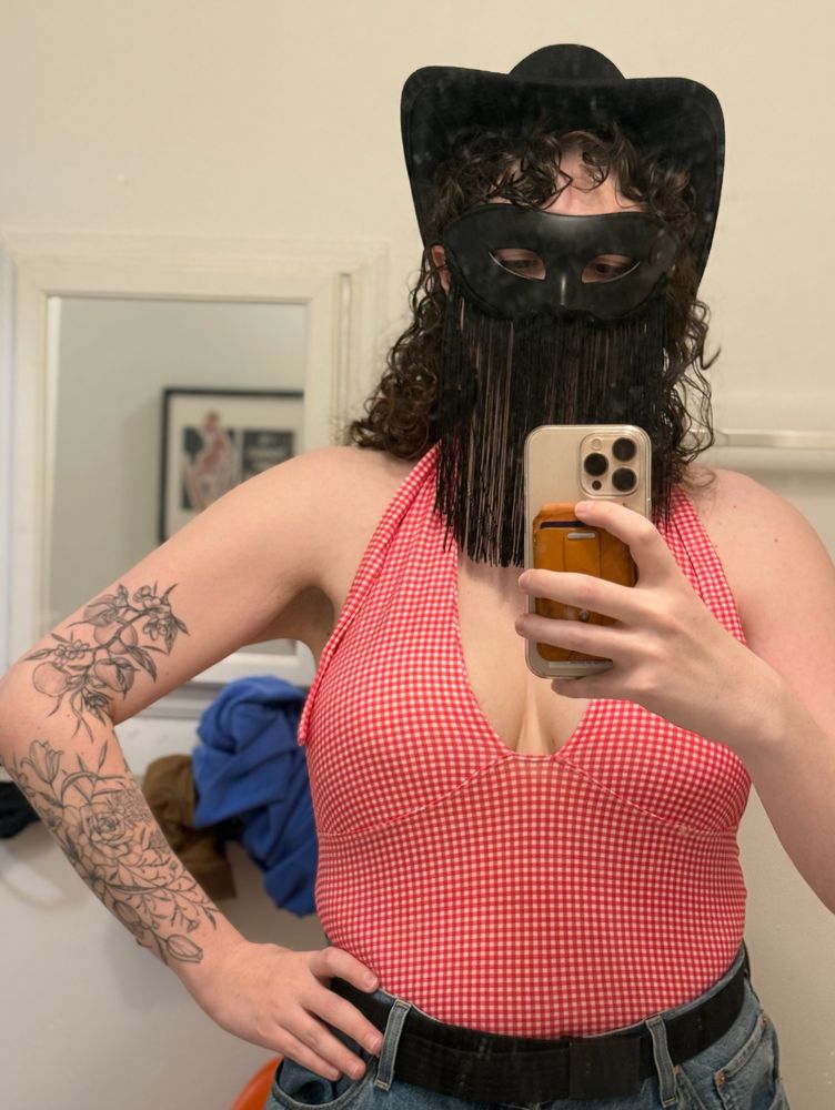 Madison wears a cowboy hat and mask with fringe on the front, like Orville Peck