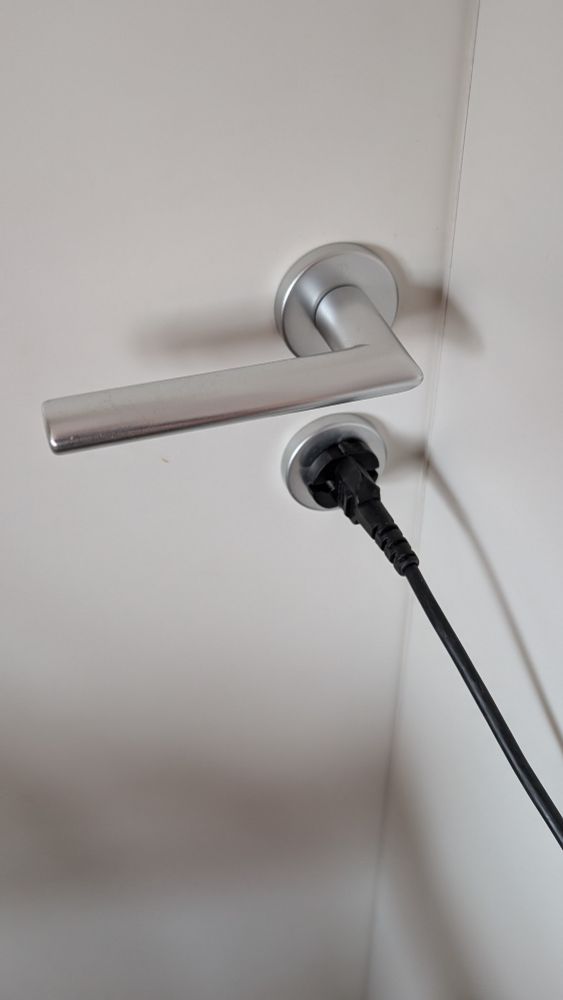 Türklinke mit Schloss darunter, darin ein Stromstecker.