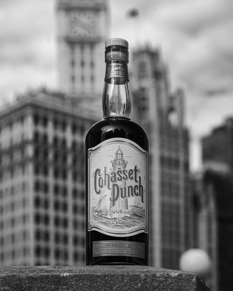 Black and white photo of a bottle of Cohasset Punch with the Wrigley Building and Tribune Tower in the background