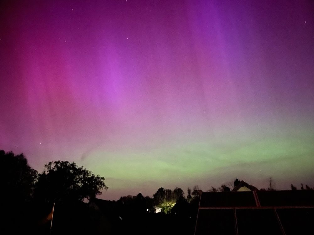 Picture of an aurora borealis. The bottom of the sky is green, the rest is shades of pink.