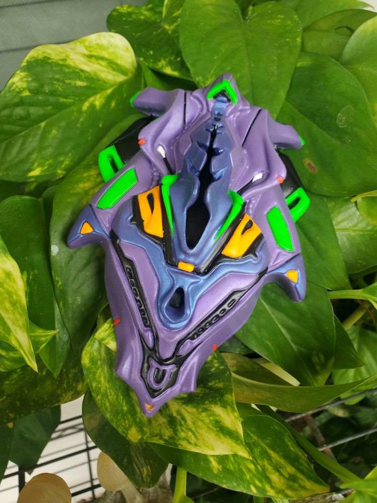 Ferrea, a robotic themed adult grinder toy model from Magic Within, in the colors of EVA-01 from NGE sits upon a bed of golden ivy leaves.