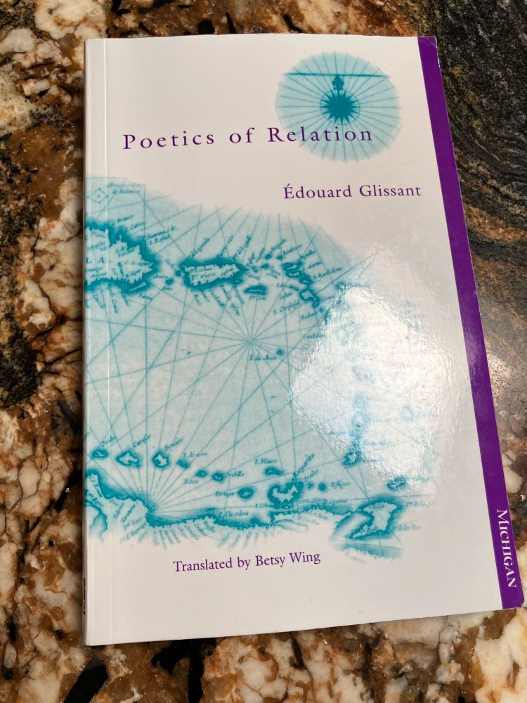 Édouard Glissant’s Poetics of Relation, translated by Betsy Wing, lays on a marble countertop. Its paperback cover is white with a light blue map of the Caribbean islands, taken from Willem Janszoon Blaeu’s 17th century _Map of the Americas_. 