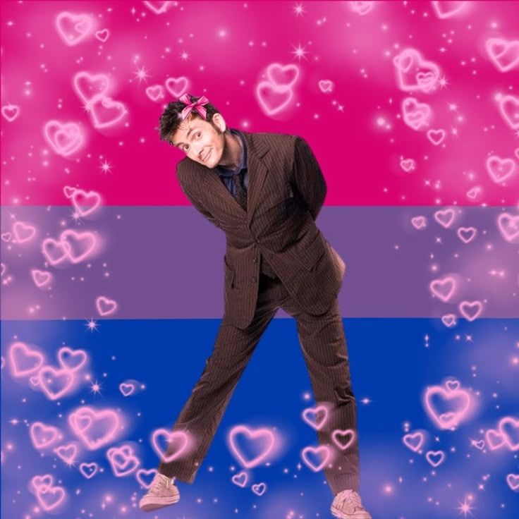 The Tenth Doctor in front of a bi pride flag.