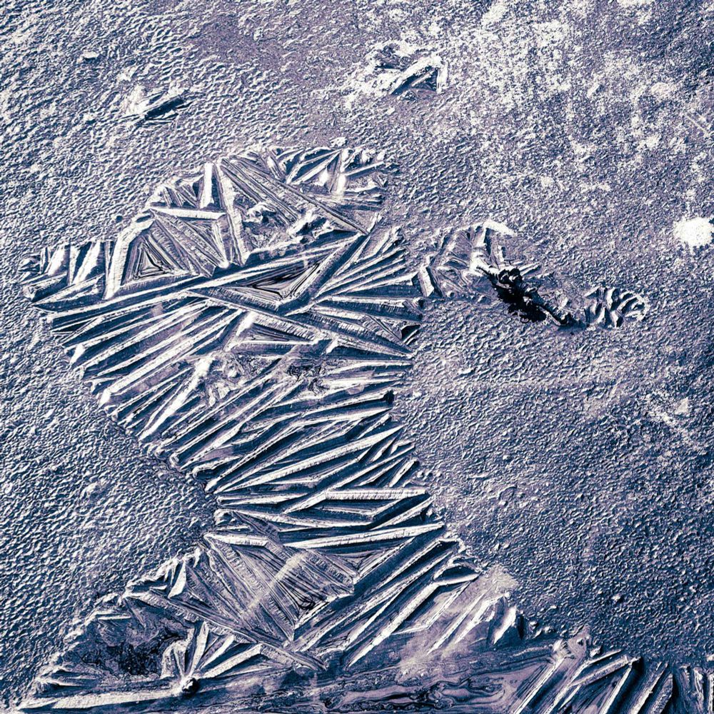 An abstract head-like shape formed from two different ice surface structures. Slightly tainted BW square photo.
