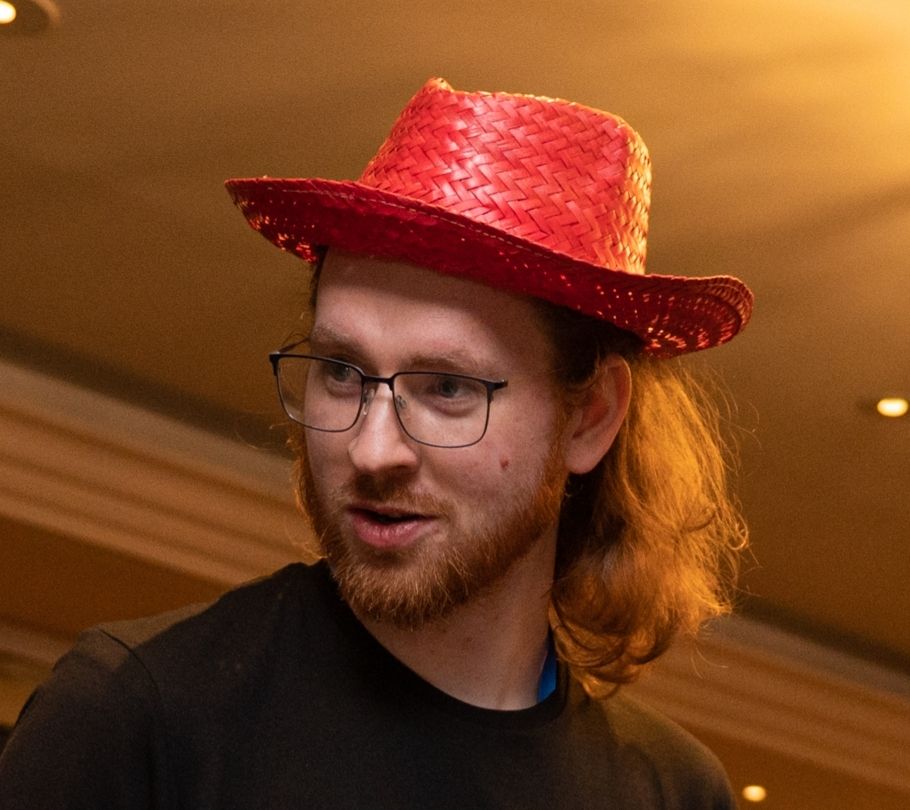 Conrad Ludgate wearing a red straw hat and a pony tail