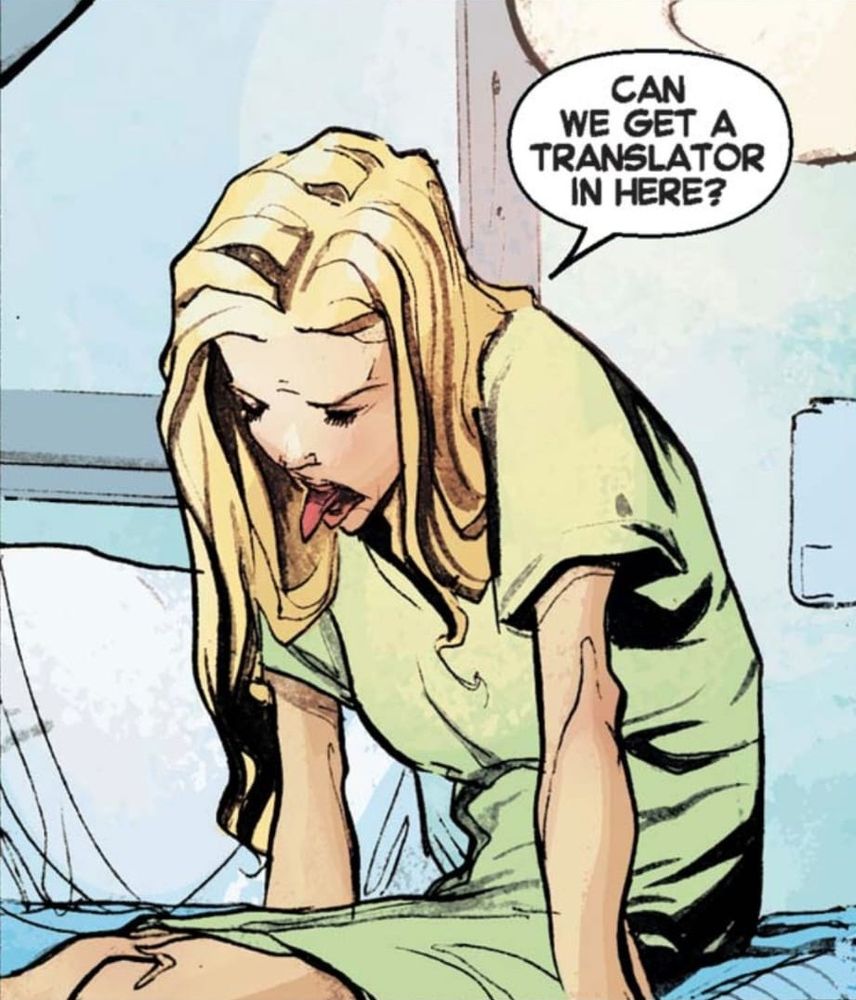 Carole Danvers, dans une blouse d'hôpital, est assise sur son lit. Elle tire la langue et dit "Can we get a translator in here?"