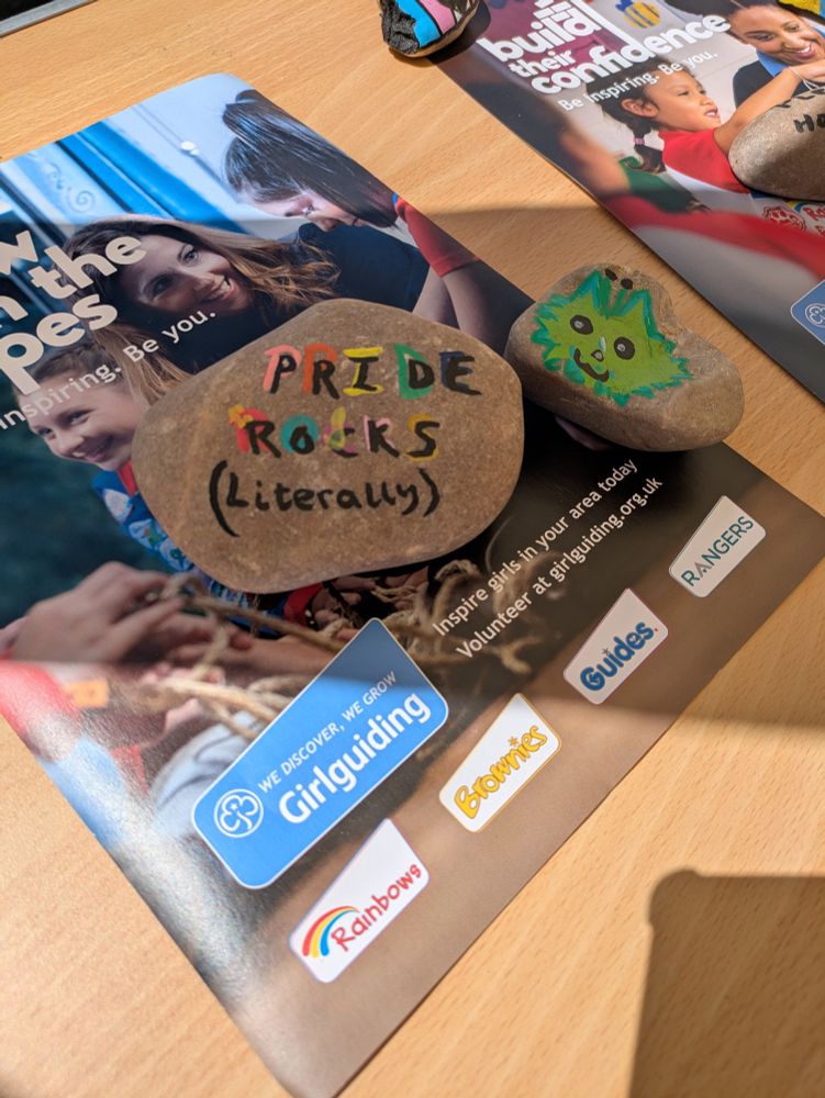 A rock which says Pride Rocks (literally) painted on it. The rock rests on a magazine for Girlguiding. 