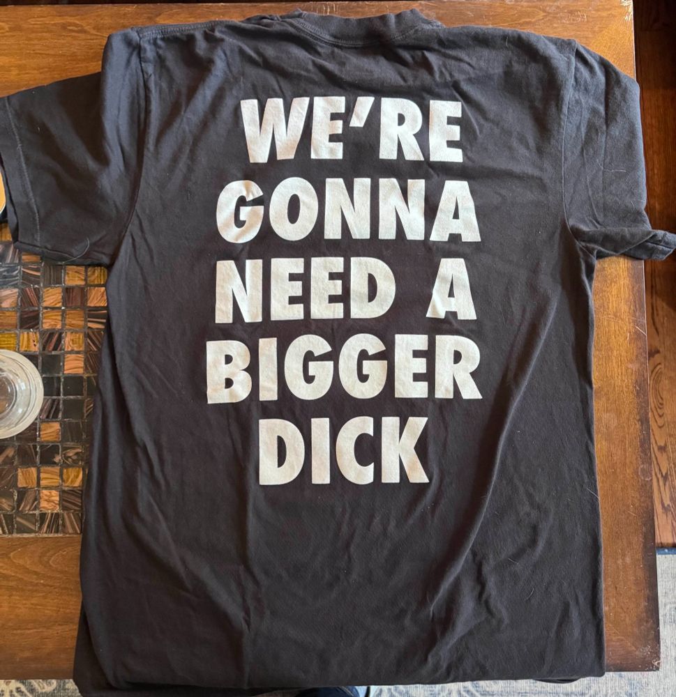 The back of the t-shirt that says "WE'RE GONNA NEED A BIGGER DICK"