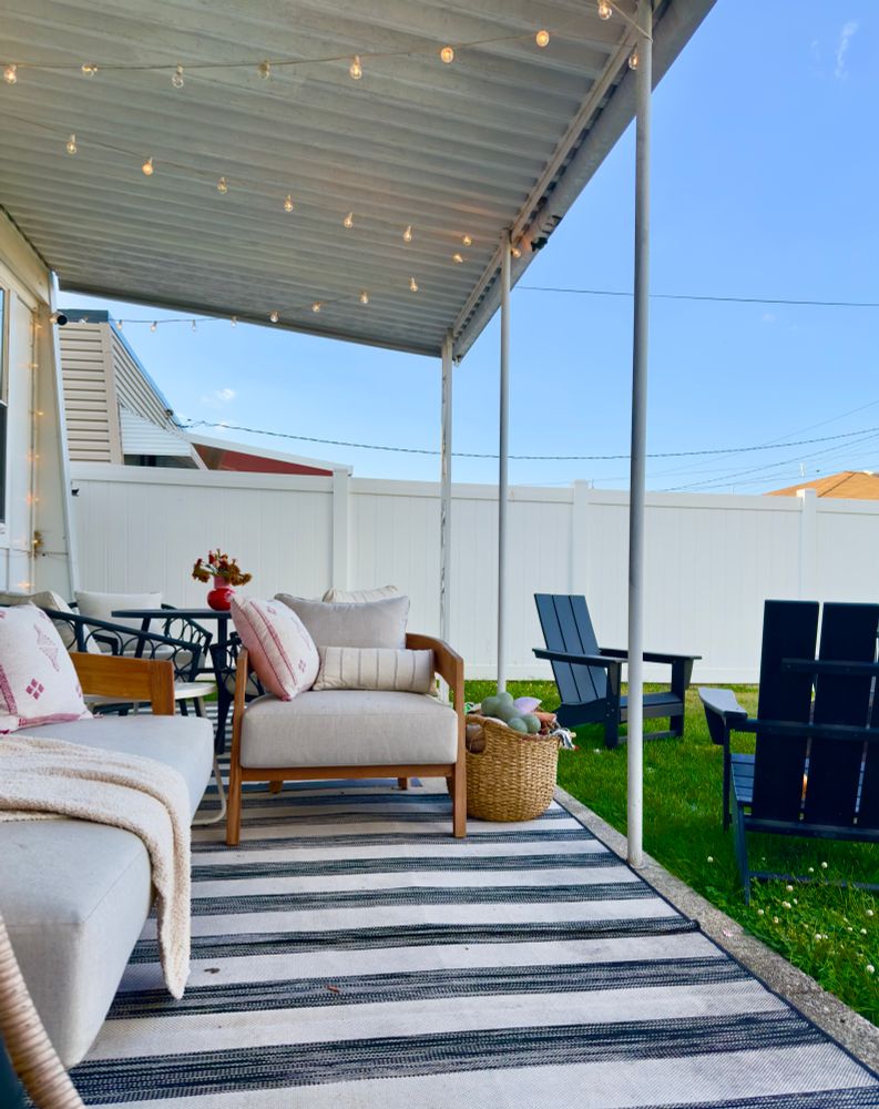 Couch and chair with light gray cushions on a patio with a black and white striped rug.
