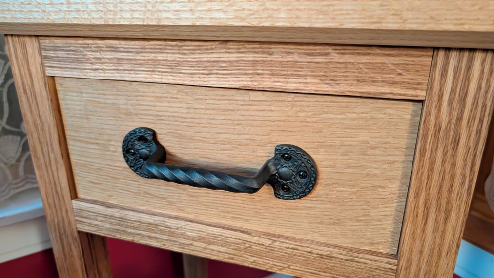 An oak phone table with a drawer. The drawer has a black cast iron pull with a licorice twisted handle and decorative ends by Louis Sullivan.