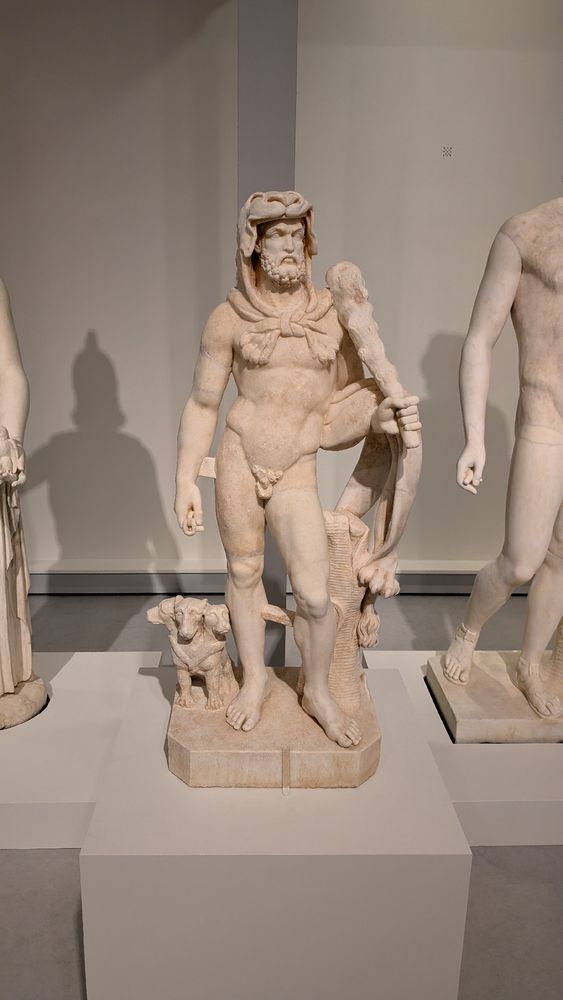 Statue of Heracles, wearing an animal skin on his head, carrying his club, with a small Cerebrus beside his leg