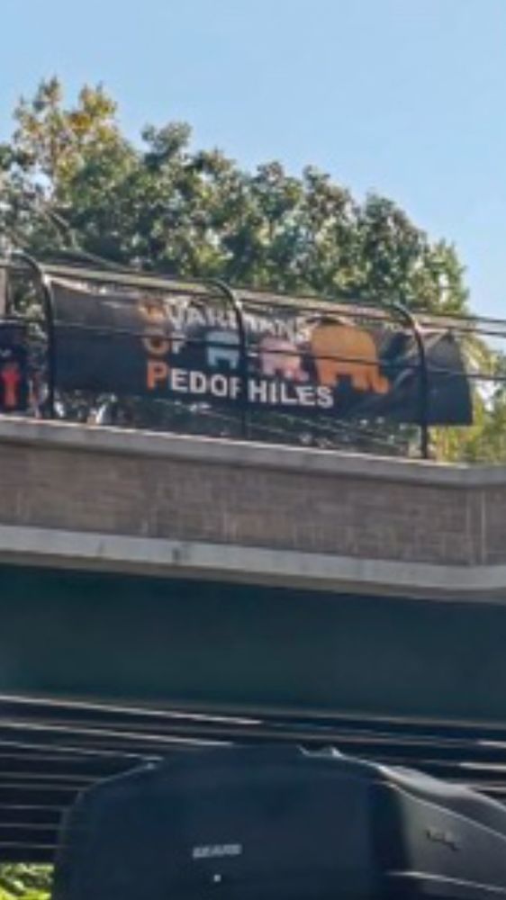 Sign on highway overpass that reads GOP - Guardians of Pedophiles with the image of a big elephant leading small elephants. 