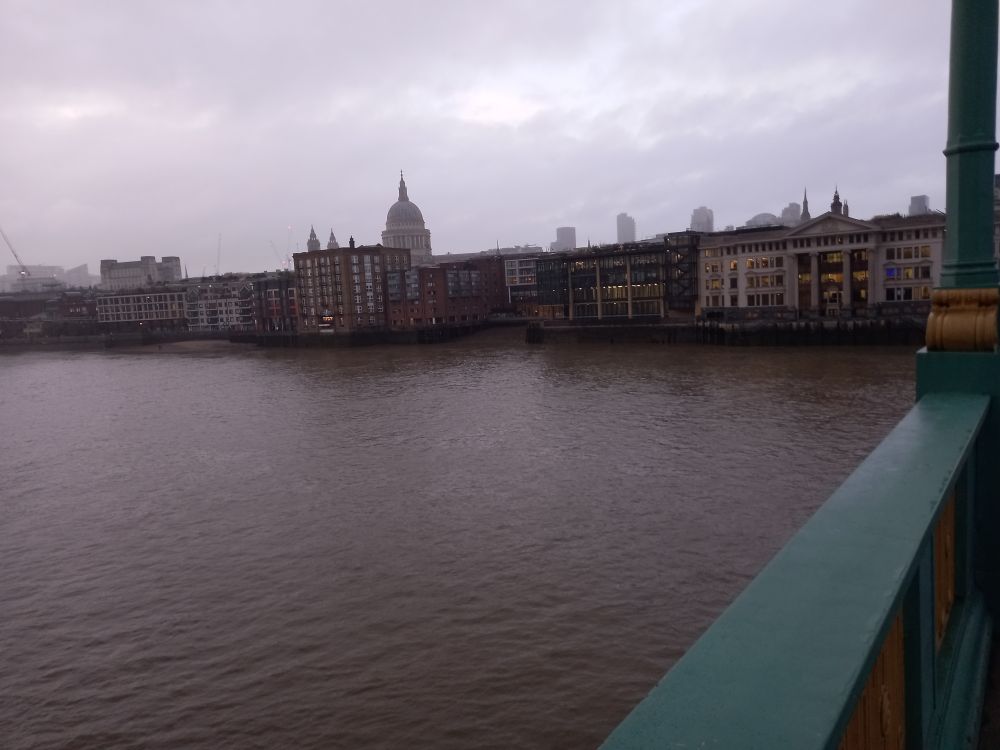 A row of buildings facing the river, four to seven stories tall, seemingly forming a solid wall. Behind the round onion dome of a big church.