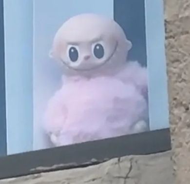 bald lafufu (fake labubu) staring out of window zoomed in