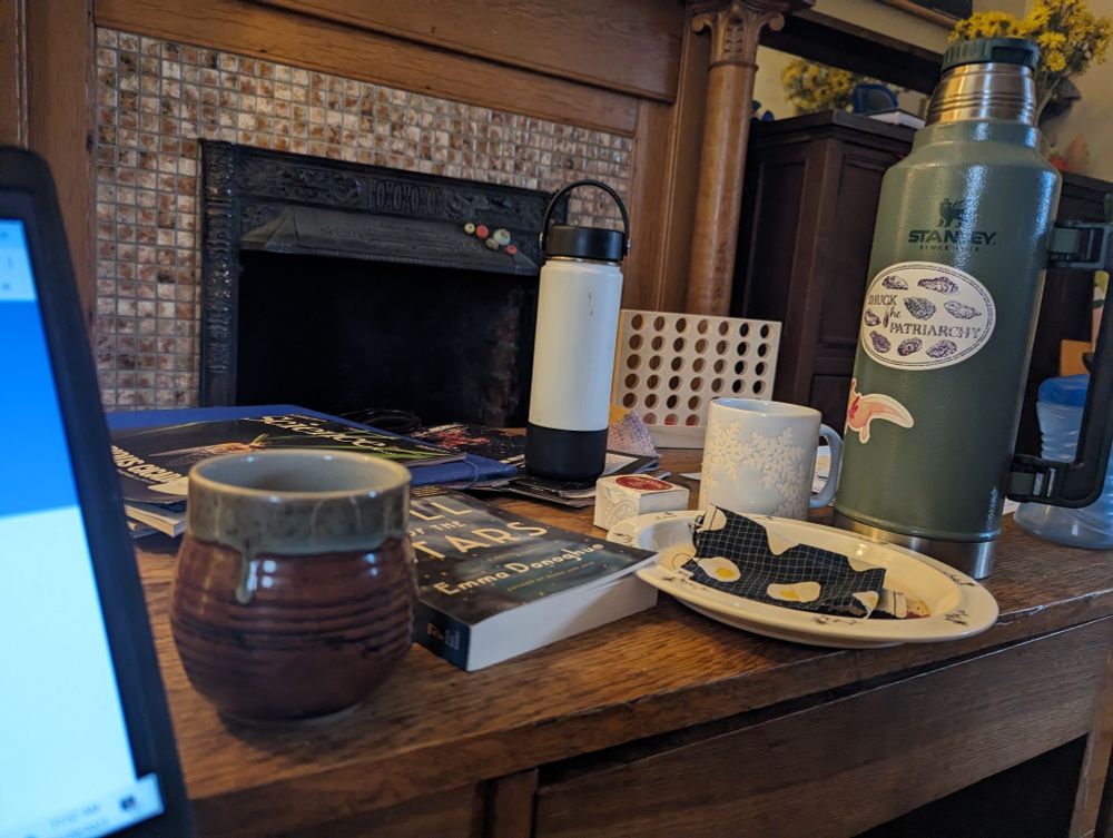 Messy table with books, journals, tea cups