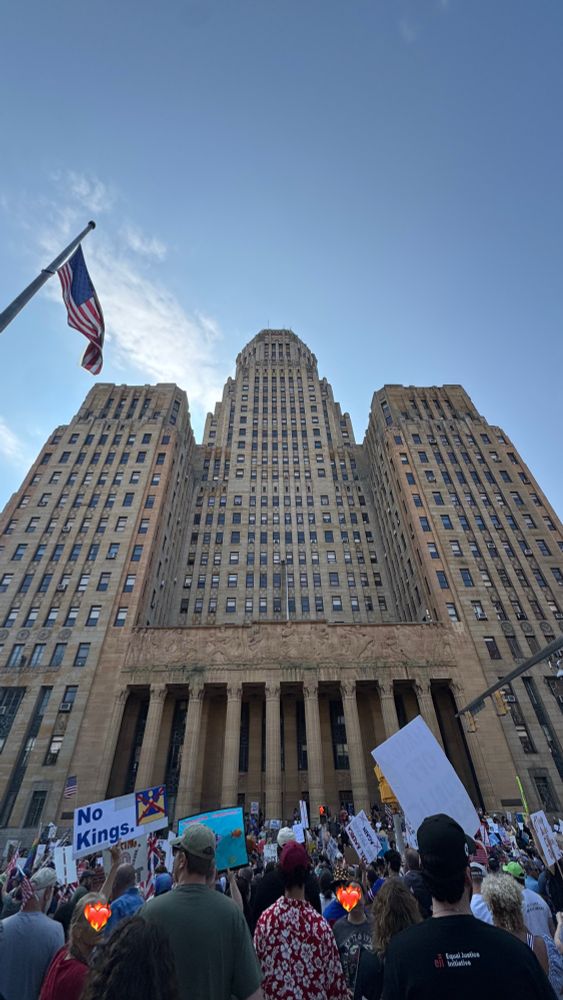 0.5 zoom photo of buffalo city hall (art deco tan building) and large no kings crowd (2 faces covered by ❤️‍🔥 emojis just in case)