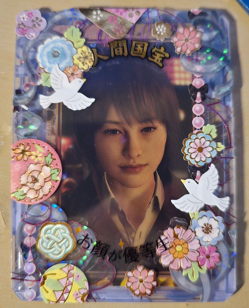 Makoto Maikmura in the 80s, she looks thoughtful. She is surrounded by ribbons and flowers. Two doves are flying away.