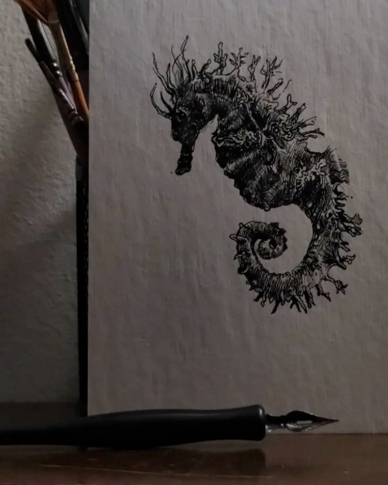 A pen drawing of a seahorse and the pen that drew it 
