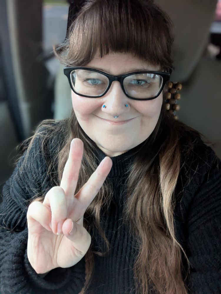 Woman smiling in a black sweater giving a peace sign